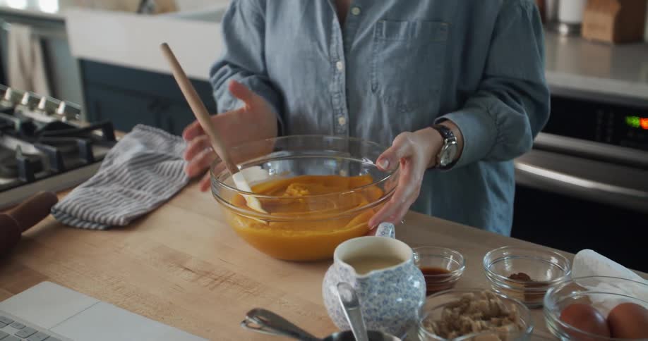 A caucasian woman baking a pumpkin dessert in a kitchen