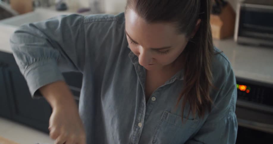 A woman standing in her kitchen at home vigorously whisks a mixture in a large bowl