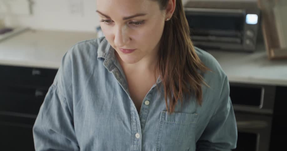 A woman looking at a laptop in a kitchen