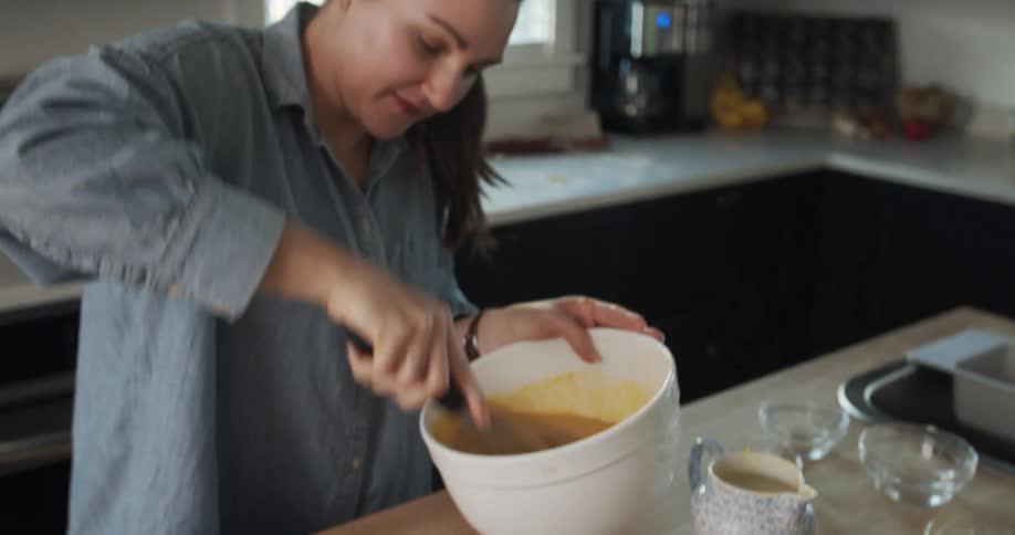 A caucasian woman in the kitchen whisking a pumpkin mixture in a bowl for a pie