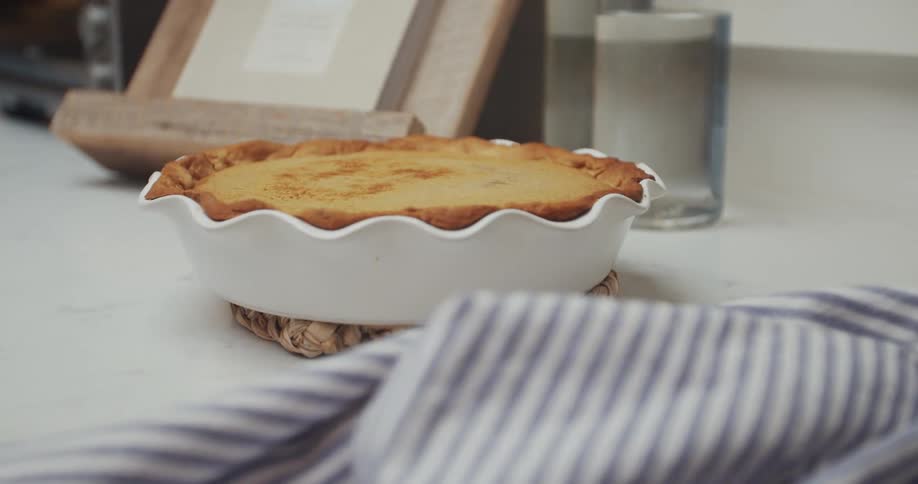 Homemade pie in a white pie dish cooling off on the counter