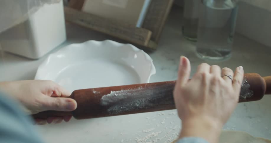 Woman at counter dust rolling pin with flour to make pie