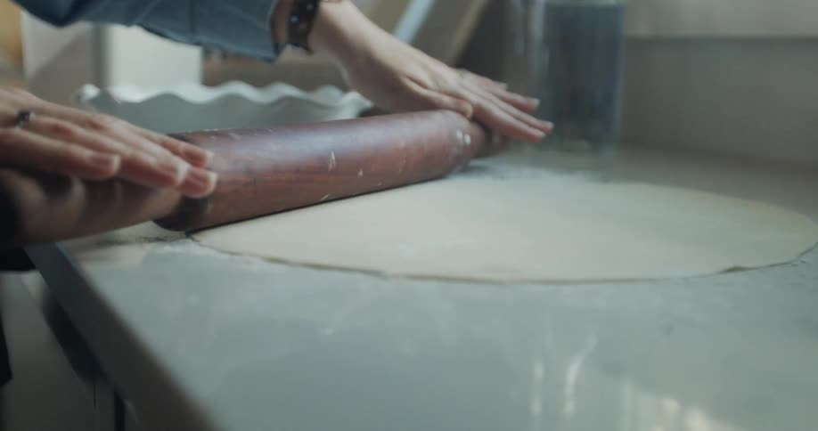 A person is rolling out dough with a rolling pin