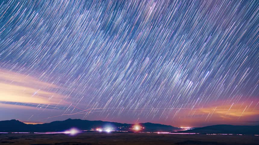 Time lapse of the stars leaving a trail on the night sky over a city