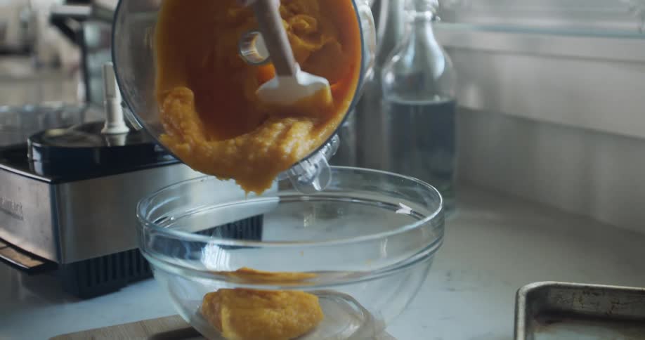 A woman puts batter in a bowl as she bakes at home