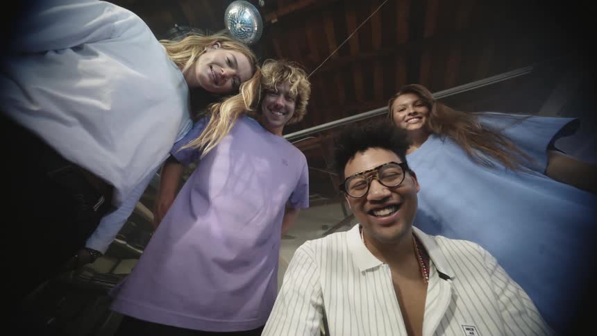 Two men and two women gathered around talking and smiling with a ceiling and a disco ball above