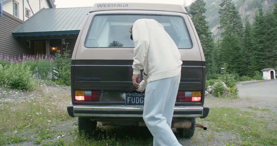 A man opens the back of his van to reveal camping equipment