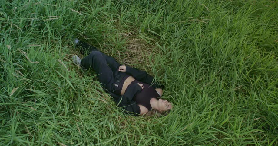 Woman is sleeping in a field with tall grass around her