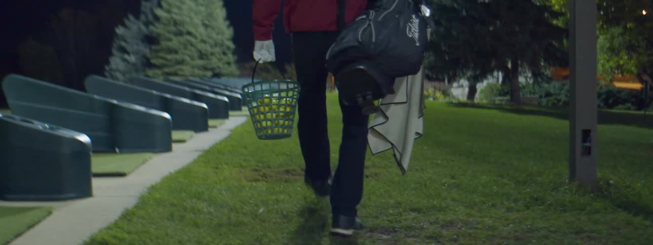 Man walking on golf course carrying golf balls