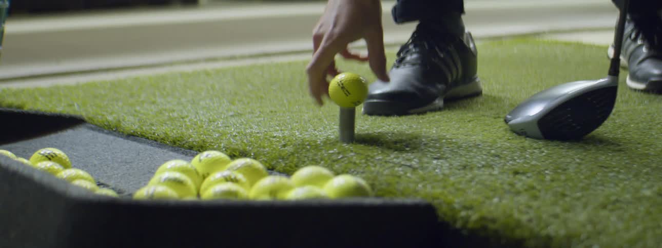 Man practicing golf in a golf driving range at night