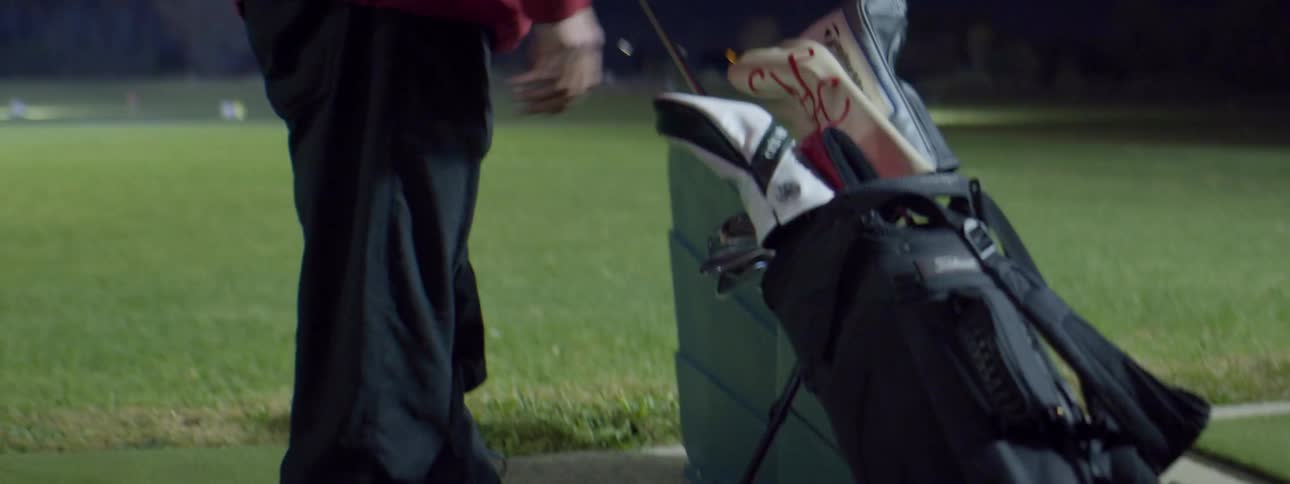 A man golfing pulls a golf club out of his bag