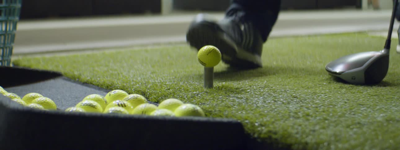 A person putting a golf ball on a tee