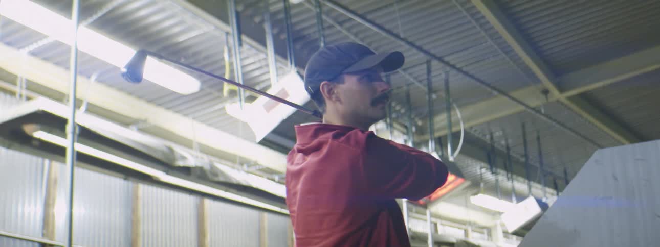 Man hitting a golf ball at a driving range