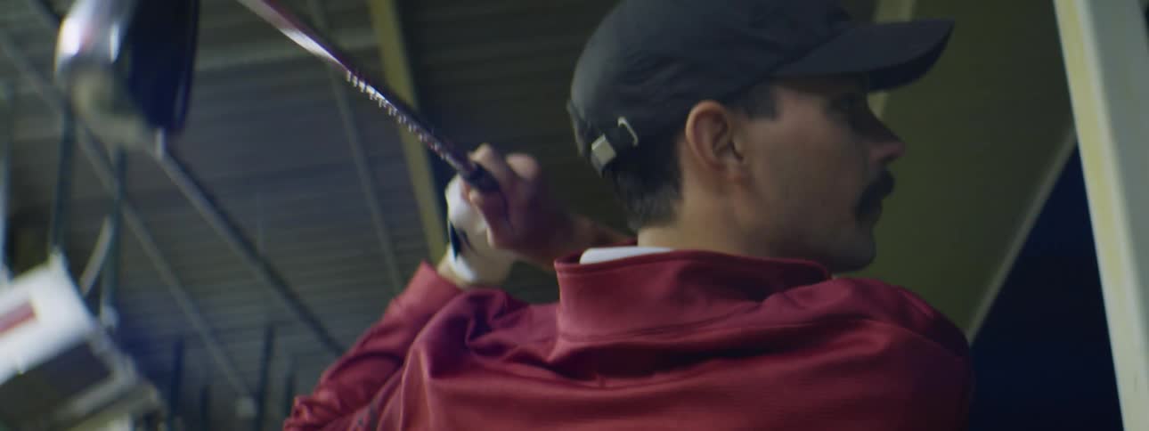 A man hits golf balls at a driving range
