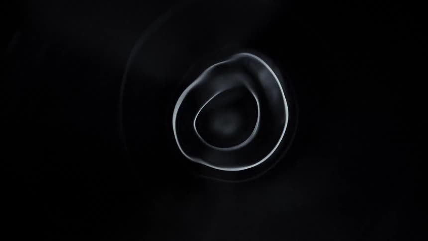 Shape composed of bright uneven concentric circles spins in blackness