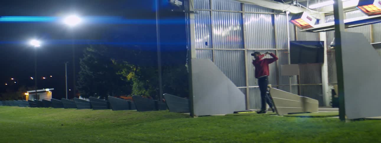 A man hitting golf balls at a driving range