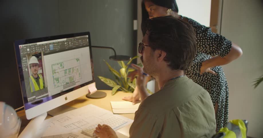 People working in an office discuss plans on a video call with a construction supervisor