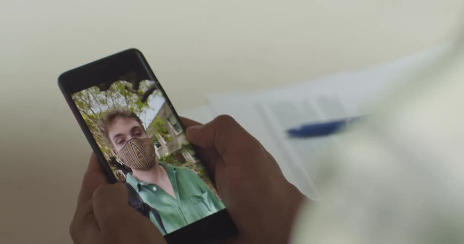 Young man wearing a face mask in a video call on a smartphone