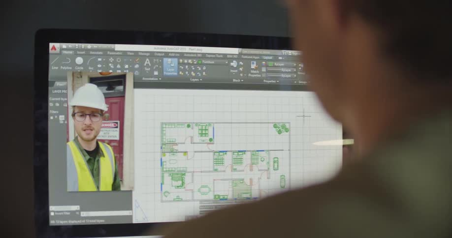 A man sits in front of a laptop discussing a floor plan