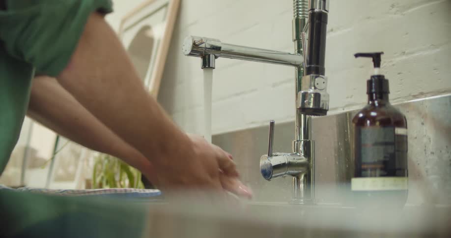 A woman washes her hands in a sink in a bathroom