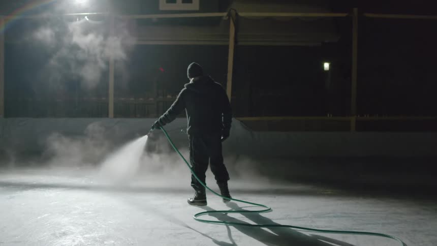 A man is cleaning the ice rink at night