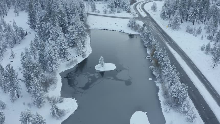 Aerial shot of a snowy forest with a road going through