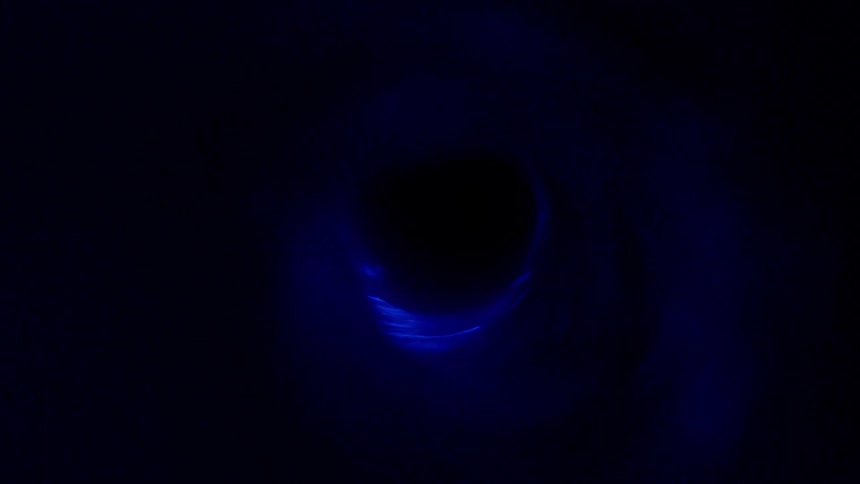Spining swirling liquid reflecting blue electric light in a dark room