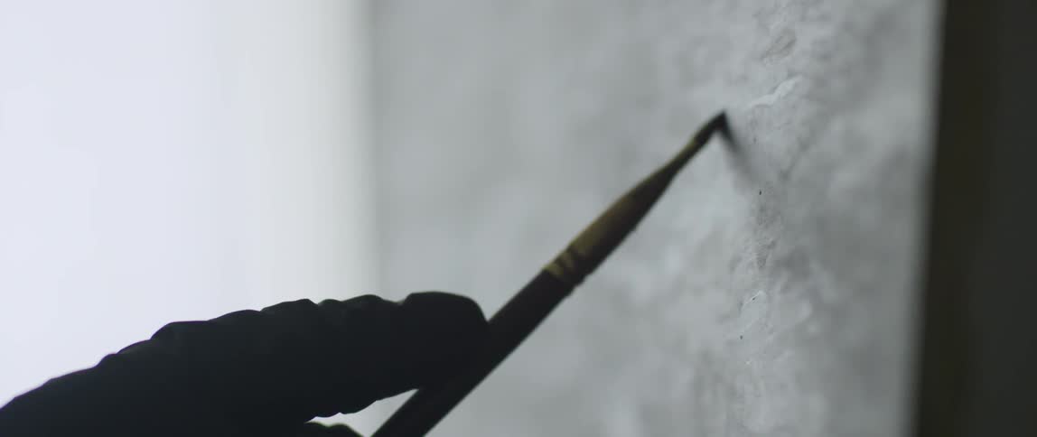 A person paints with a small paintbrush