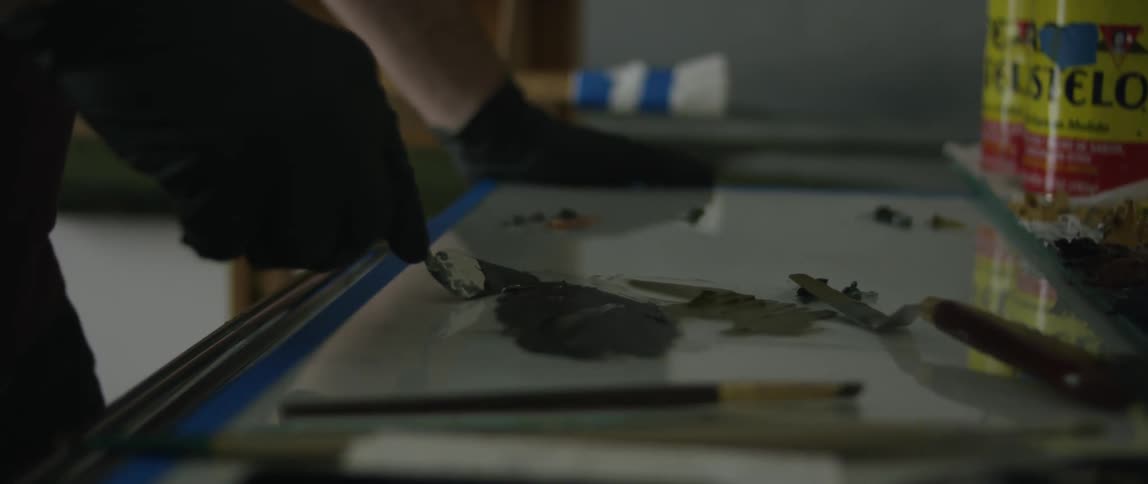 Person mixing paint with a mixing tool