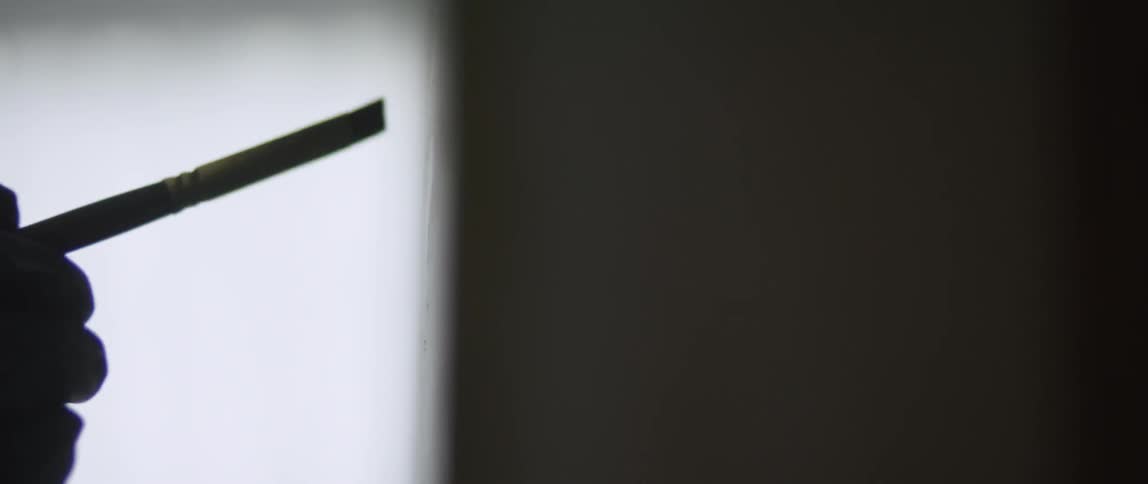 A paint brush is placed against a canvas