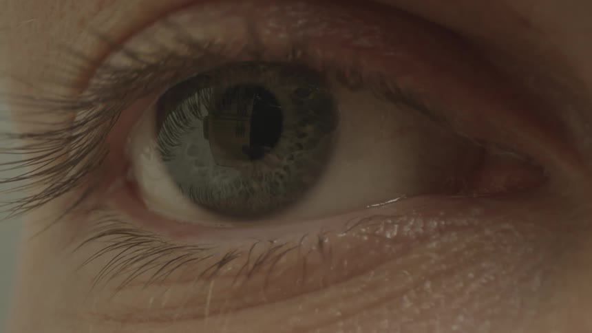 Extreme close up of the green eye of a woman reading