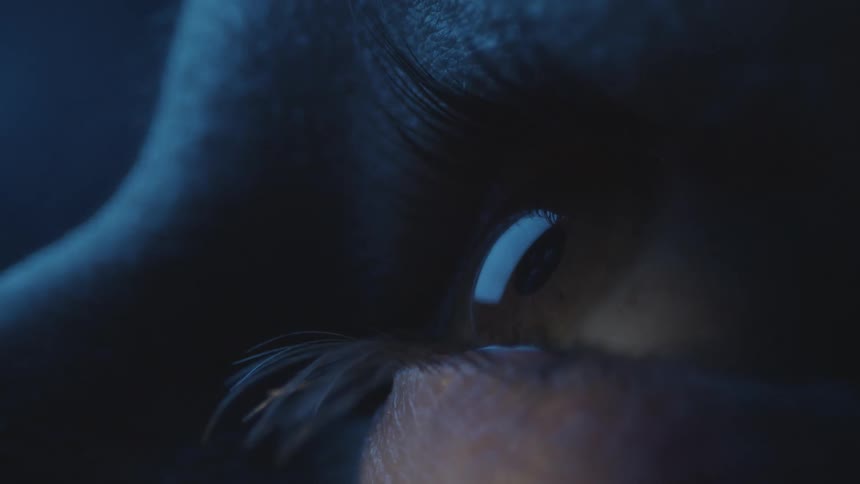 Extreme close up of the hazel eye of a woman looking at a screen