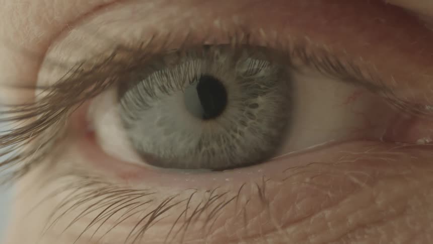 Close up of an eyelid opening to reveal a blue eye
