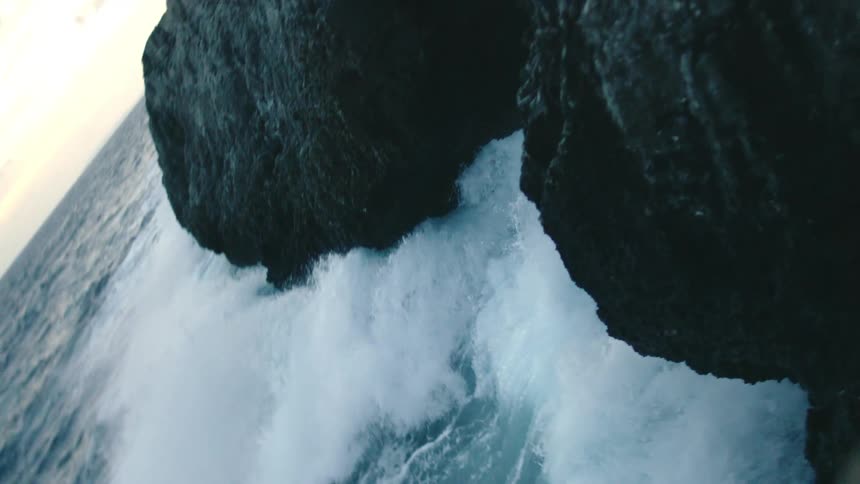 Waves crashing against a black rock formation