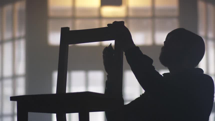 A carpenter sanding a chair