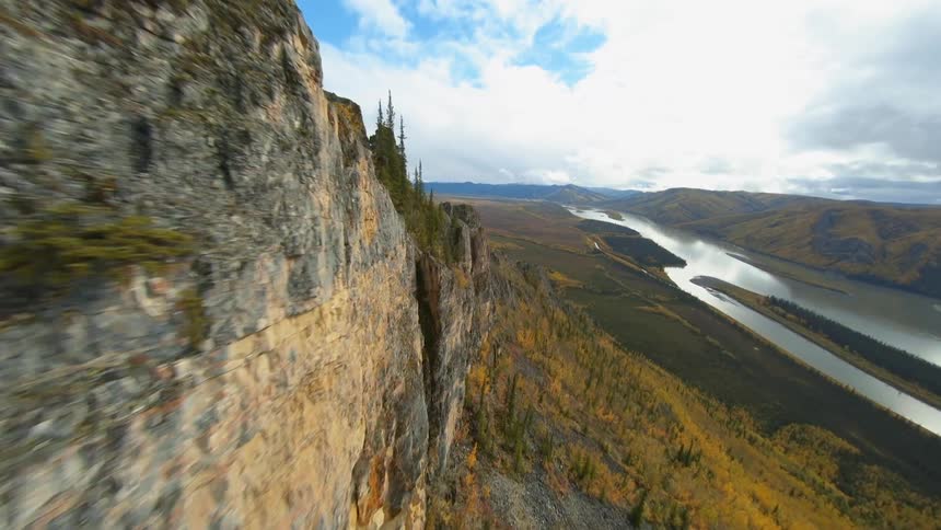 An aerial view of a cliff with fall trees above a river