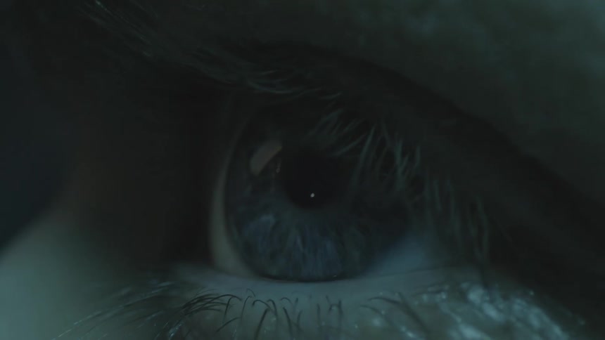 Close up of a womans hazel eye looking at a screen in a dark room