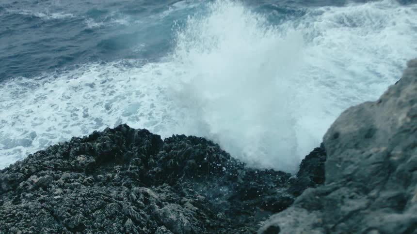 Water spraying up the side of a cliff on the shore
