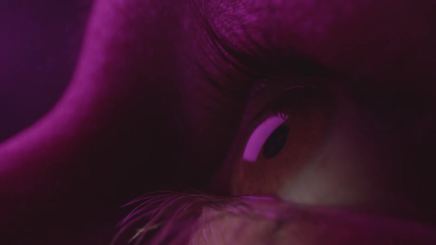 A close up of a persons eye as lights dim and change colors