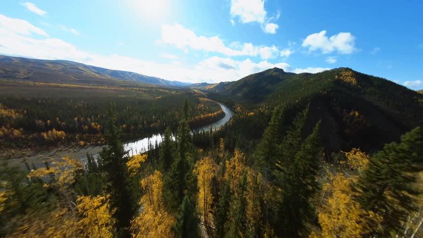 A river runs through a verdant countryside on a sunny day
