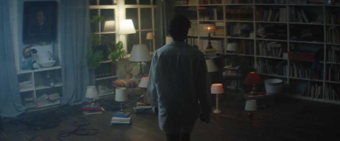A woman stands in shock as dozen of lamps are randomly placed and flashing in her living room at night