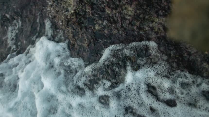 Coastal rocks with foamy waves rolling over