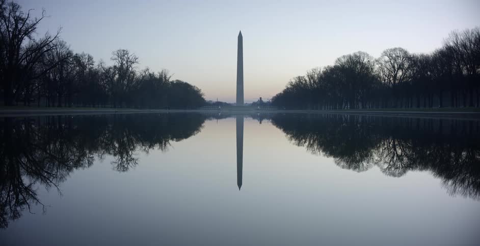 A pond surrounded by trees with the lincoln memorial the sky and clouds in the background