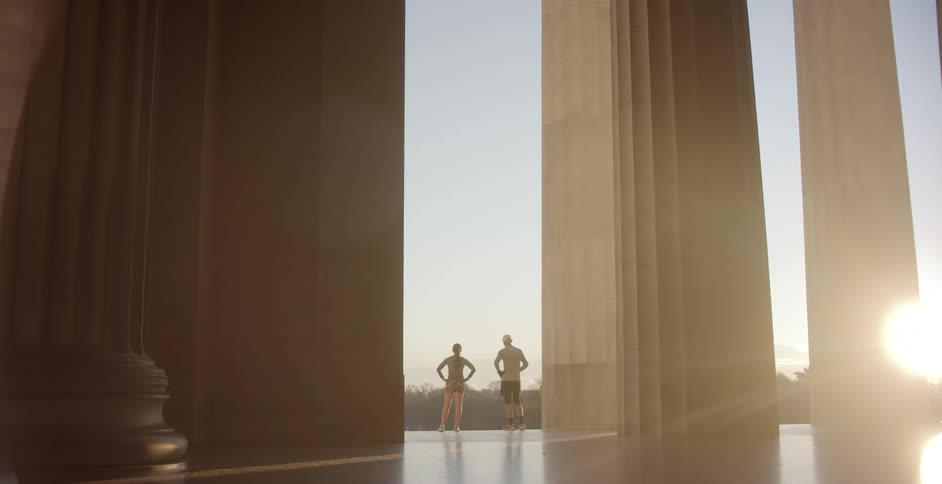 A man and woman stand on the edge of a long corridor and look out at the landscape