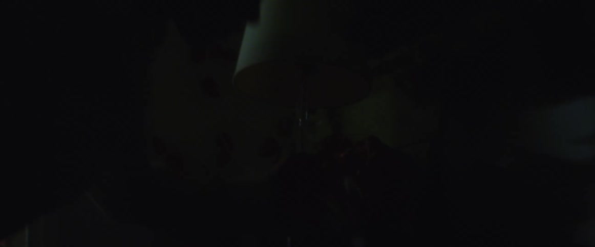 A person unplugs a lamp sitting on a table next to a glass figurine