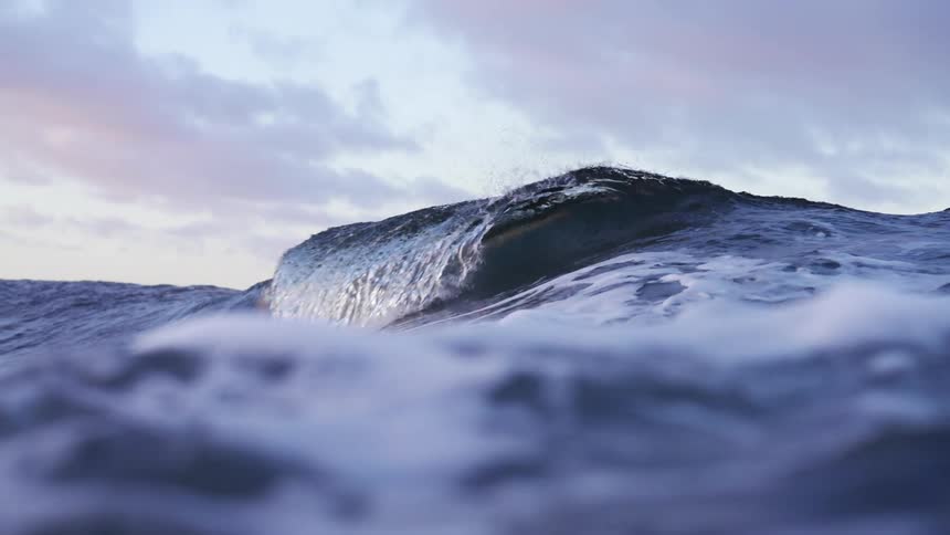 Ocean wave rolls in splashing on a cloudy day
