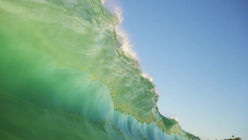 Floating on the water with a wave crashing down and the shore off in the distance