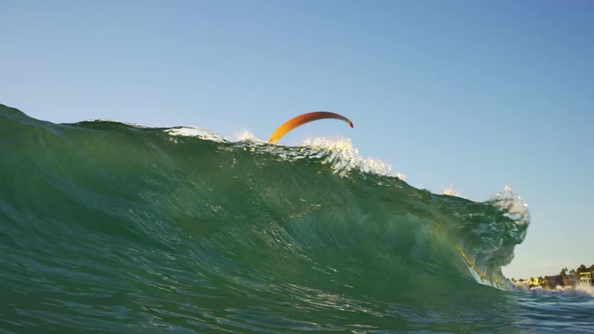 Paragliders hovering over the ocean waves crashing on the coast