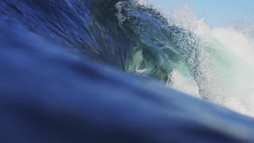 Wave crashing on the surface of the blue ocean waters