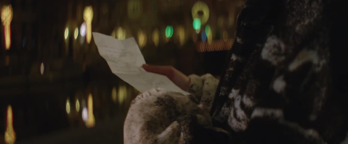 A black woman standing in front a tall building in the city reading a letter